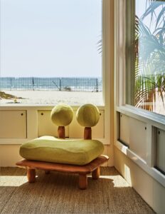 Uniquely designed chair positioned by a large window at Kelly Wearstler's Surf Shack, photographed by The Ingalls, offering a stunning view of the ocean and embodying mid-century modern aesthetics.