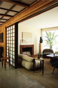 View of the living room at Kelly Wearstler's Surf Shack, captured by The Ingalls, featuring mid-century modern design elements, large windows, and an inviting ambiance that opens up to the stunning Malibu coastline